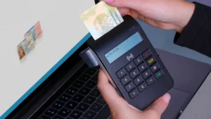 Person using contactless device for ID payment verification on a laptop.