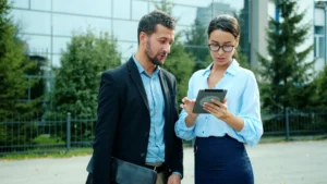 Two colleagues discussing a tablet outside office building