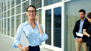 Woman in glasses talking on phone outside office building