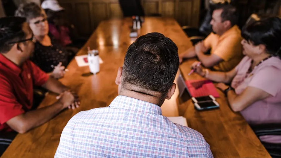 A business meeting with a diverse team discussing around a wooden table in an office setting.