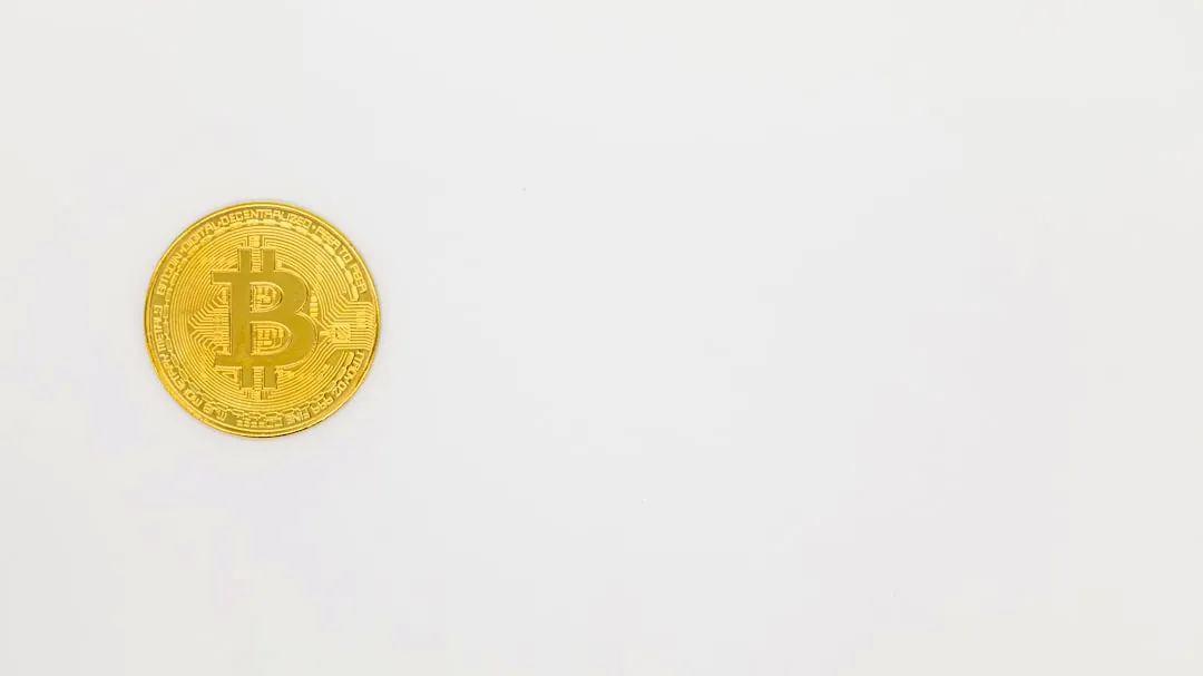 a gold bit coin sitting on top of a white surface