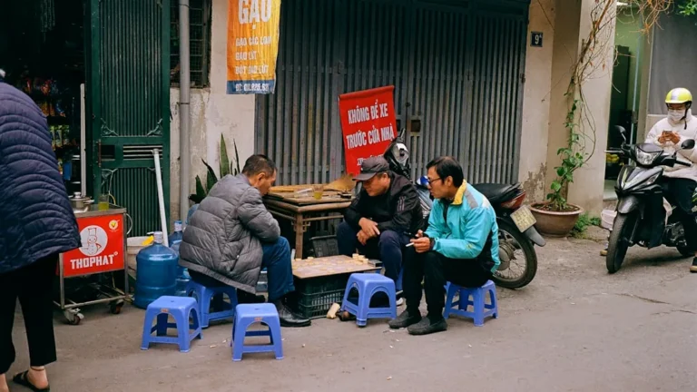 A group of people sitting on blue stools in front of a building