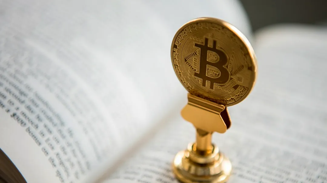 bitcoin on gold stand on top of book