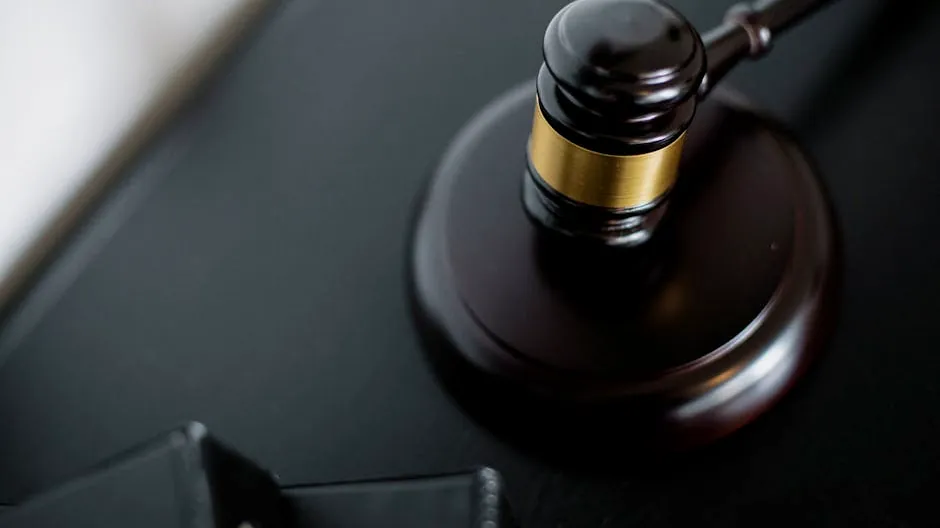 Close-up of a wooden judge's gavel on a black desk, symbolizing justice and law.