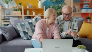 Elderly couple shopping online with credit card and laptop.