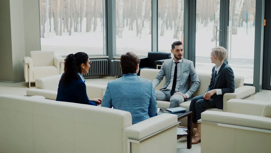 Four professionals in a modern office meeting space.
