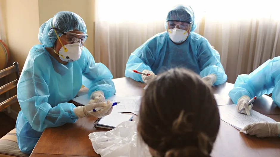 Healthcare professionals in PPE discuss operations during a meeting indoors.