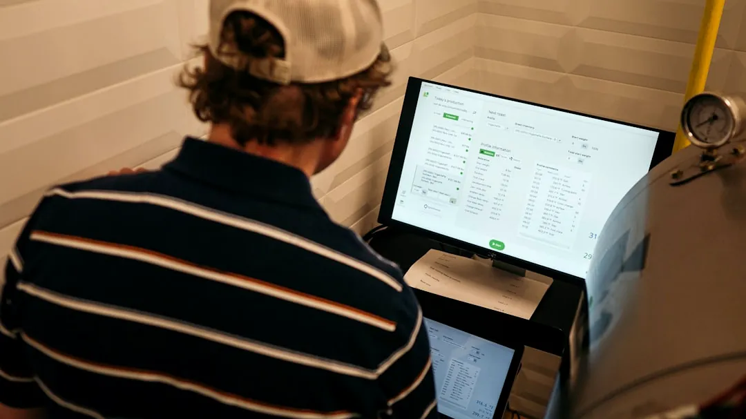 man in white and black striped polo shirt in front of monitor