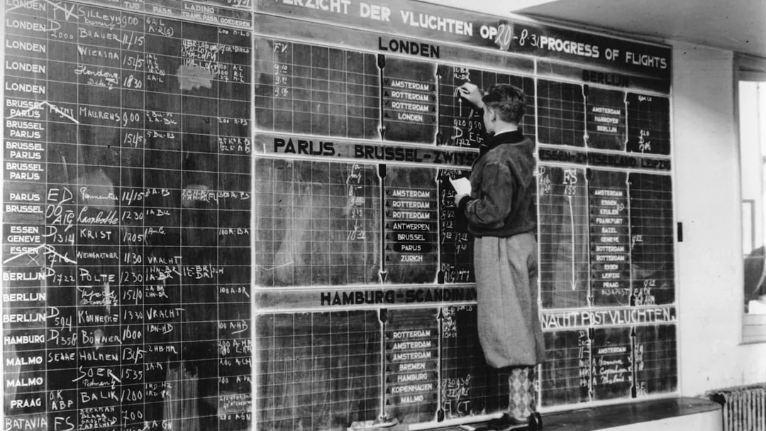 Man updates flight departure board with chalk