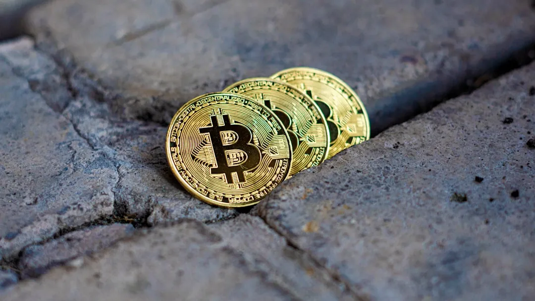 Three gold bitcoin coins on textured surface