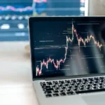 A laptop on a desk showing detailed cryptocurrency graphs for data analysis.