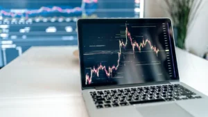 A laptop on a desk showing detailed cryptocurrency graphs for data analysis.