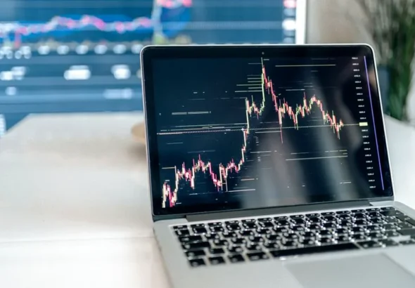 A laptop on a desk showing detailed cryptocurrency graphs for data analysis.