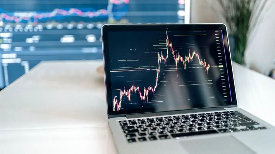 A laptop on a desk showing detailed cryptocurrency graphs for data analysis.