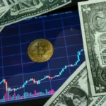 Bitcoin coin on a tablet showing stock chart, surrounded by dollar bills.