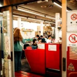 People inside a store with a red counter.